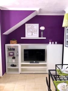 a living room with a tv and purple wall at Mar Azul in Chiclana de la Frontera
