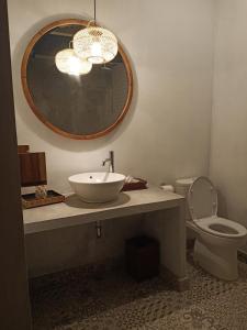 a bathroom with a sink and a toilet and a mirror at THE OWN PENIDA COTTAGE & SPA in Nusa Penida