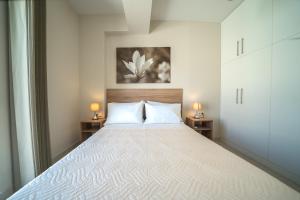 sypialnia z dużym białym łóżkiem z 2 lampami w obiekcie Alma City Center Apartment's w Heraklionie