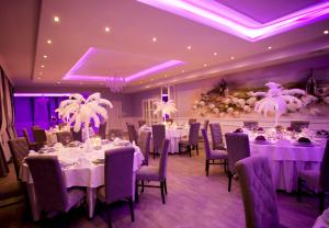 a banquet room with white tables and chairs and purple lighting at Dworek Rajska Góra in Wejherowo
