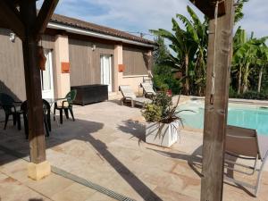 een terras met een tafel en stoelen en een zwembad bij La Maison de Joindy in Saint-Cyprien