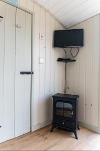 a room with a stove and a tv on a wall at Hilltop Hut in Church Stretton