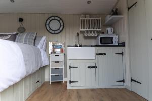a bedroom with a bed and a kitchen with a microwave at Hilltop Hut in Church Stretton