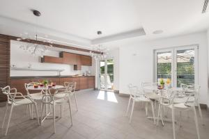 a kitchen and dining room with white tables and chairs at Plage Lovran Residence in Lovran