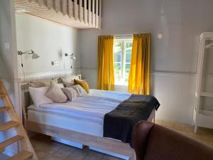 een slaapkamer met een bed en een raam met gele gordijnen bij Wallby Säteri in Skirö