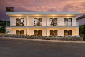 une maison blanche avec un coucher de soleil en arrière-plan dans l'établissement Sigma Luxury Rooms, à Sivota