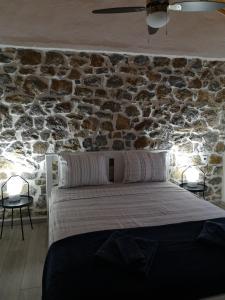 a bed in a room with a stone wall at Mandal Cottage in Samothraki