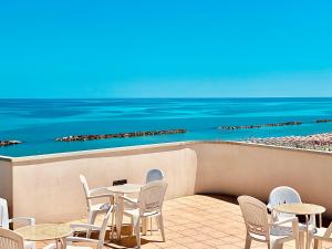 a dining room table with chairs and a balcony overlooking the ocean at Hotel Ambassador in Grottammare