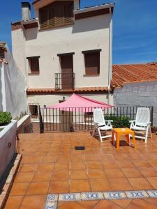 een patio met 2 stoelen en een tafel en een roze tent bij LA CASA DEL LILO in Navamorcuende