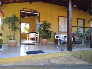 a restaurant with a yellow wall with chairs and plants at Pousada Licuri in Serra do Cipo