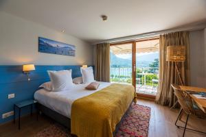 a hotel room with a bed and a large window at Hôtel Beau Site Talloires B SPA in Talloires