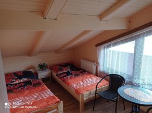 two beds in a room with a table and a window at Penzión Sarka in Štrba