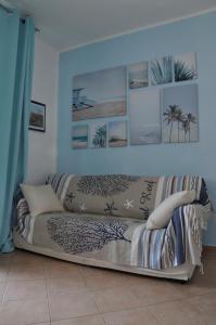 un sofá en una sala de estar con fotos en la pared en La casa azzurra en Cogoleto