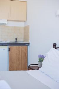 a bedroom with a white bed and a kitchen at Villa Aegeo Studios in Batsi