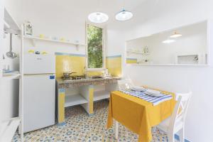 une petite cuisine avec une table jaune, une table jaune et une chaise jaune dans l'établissement Le Querce, à Procida