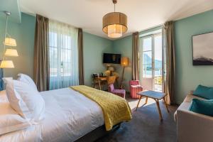 a bedroom with a bed and a chair and a desk at Hôtel Beau Site Talloires B SPA in Talloires