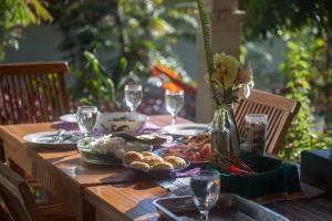 einen Holztisch mit Essen und Weingläsern darauf in der Unterkunft Ara Garden Inn, Accommodation, Yoga studio & Spa in Ruteng