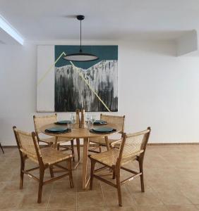 un comedor con mesa, sillas y una pintura en Apartamento Espaçoso Sesimbra en Sesimbra