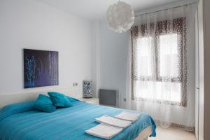 a bedroom with a blue bed with towels on it at Real de Cartuja Apartments & Suites in Granada