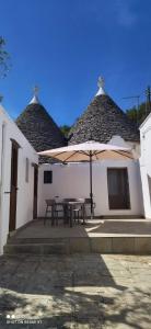 a patio with a table and an umbrella at Trulli di nonno Ciccio in Cisternino