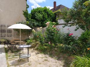 einen Garten mit zwei Tischen und einem Sonnenschirm in der Unterkunft Atelier Keszthely in Keszthely