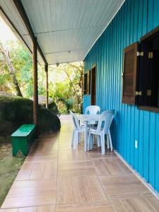 a patio with a table and chairs on a blue wall at Chalé Mar e Montanha in Trindade
