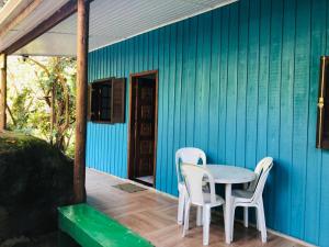a blue house with a table and chairs on a porch at Chalé Mar e Montanha in Trindade