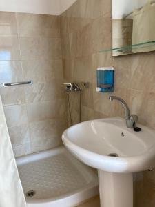 a bathroom with a sink and a shower and a tub at Hotel Galini in Póros Kefalonias