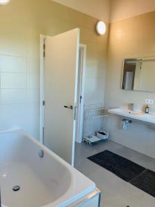 een witte badkamer met een bad en een wastafel bij Landlord in Holsbeek