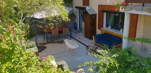 un patio con un sofá azul y una mesa en Le petit appart de Pomme, en Embrun