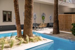 a swimming pool with palm trees in a house at Cocoon City Hostel in Chania