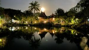 a house in the middle of a lake at night at Baan Thai House in Phra Nakhon Si Ayutthaya
