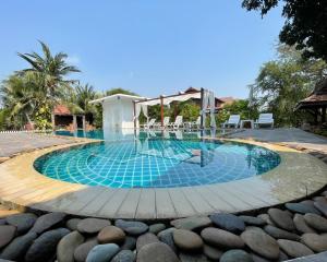 a swimming pool with chairs and rocks around it at Baan Thai House in Phra Nakhon Si Ayutthaya