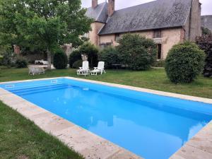 una piscina azul frente a una casa en Ancien Presbytère, en La Chapelle-dʼAngillon