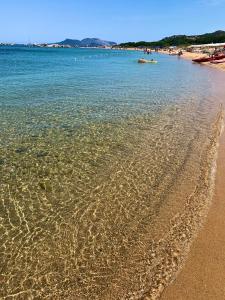 una spiaggia con sabbia e acqua di Sardegna Costa Corallina Appartamento Luxury Vista Mare in splendido villaggio - IUN R6511 a Costa Corallina