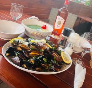 a plate of mussels on a table with a bottle of wine at Casa Roman II by the sea in Costinesti