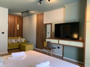 a bedroom with a bed with a television and a couch at Bluetique Apartments Himara in Himare