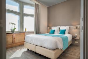 a bedroom with a large bed with blue pillows at Hotel Maraboe in Bruges