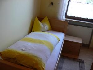 um quarto com uma cama com lençóis amarelos e uma janela em Pension zur Einkehr em Allersberg