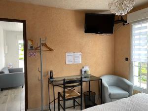 um quarto com uma mesa e uma televisão na parede em Studio indépendant chez l'habitant em Olivet