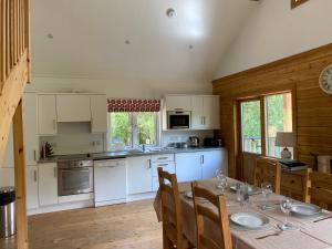 una cocina con armarios blancos y una mesa con sillas. en Hatton Lodge, en Dunkeld