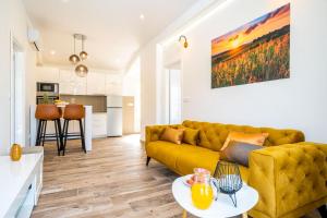 a living room with a yellow couch and a kitchen at Corallium Lux in Pomena