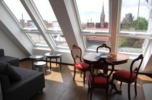 een woonkamer met een tafel, stoelen en ramen bij Kunsthaus Apartments in Wenen