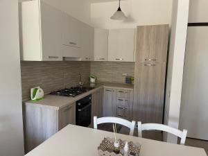 a kitchen with white cabinets and a white table with chairs at Delia's house in Drapia