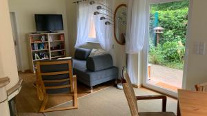 a living room with a chair and a television and a window at Ruhiges Ferienhaus Wandlitz in Wandlitz