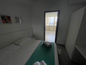 een witte slaapkamer met een bed met een groene deken bij Evergreen in Roseto Capo Spulico