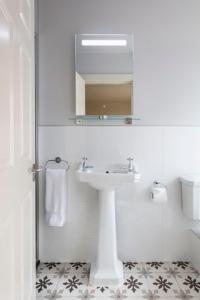 Baño blanco con lavabo y espejo en Lagom Restaurant & Townhouse en Kenmare