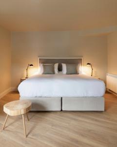 a bedroom with a large white bed and a wooden stool at Lagom Restaurant & Townhouse in Kenmare