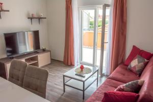 a living room with a red couch and a tv at Apartman Joso 3 in Sukošan