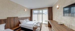 a hotel room with a bed and a desk with a phone at Hotel Pautalia in Sunny Beach